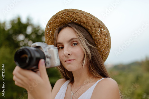 A Young Woman Wearing a Straw Hat is Enjoying Capturing Beautiful Moments with Her Camera