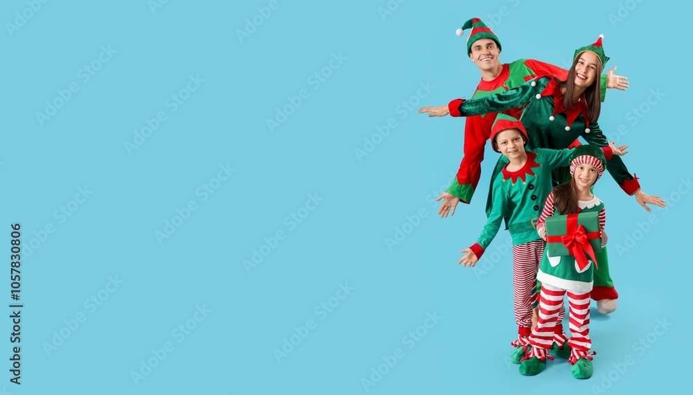 Happy family in elf's costumes and with gift having fun on blue background with space for text Happy family in elf's costumes and with gift having fun on blue background with space for text