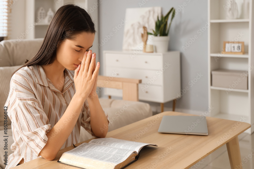 Beautiful young woman reading Bible and praying at home Beautiful young woman reading Bible and praying at home