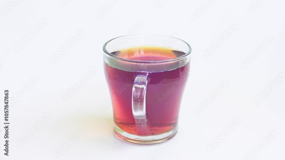 Transparent mug of strong brewed tea spins in a circle on a white background. Medium shot Transparent mug of strong brewed tea spins in a circle on a white background. Medium shot