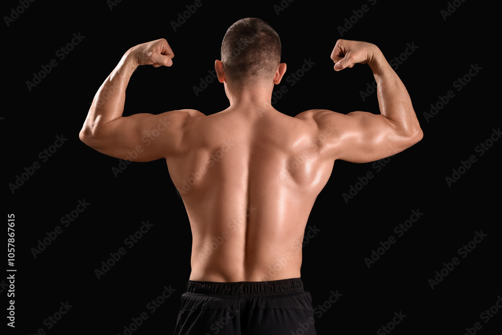 Fototapeta premium Male bodybuilder showing muscles on dark background, back view