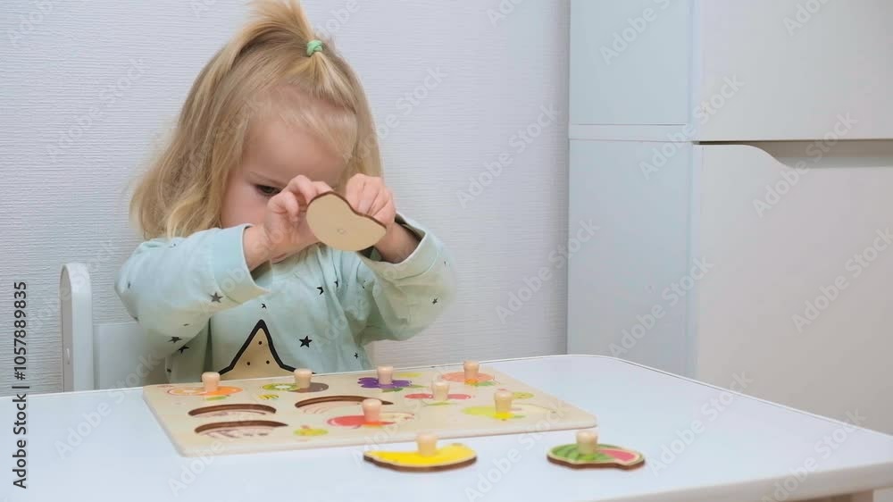 Little child toddler girl two-year-old sits at a table and plays with toys of different colors, the mental development of children. Little child toddler girl two-year-old sits at a table and plays with toys of different colors, the mental development of children.