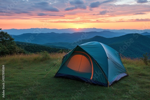 A tent set up on a grassy hilltop with stunning sunset views over mountains