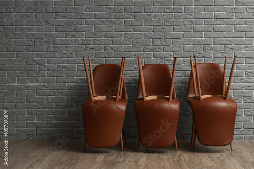 Stylish chairs upside down near grey brick wall