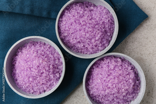 Bowls with sea salt and napkin on light background, closeup