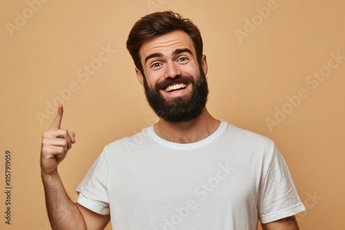 Young man smiling and gesturing to the right against a plain background in a ...