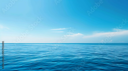 Deep blue ocean with a clear blue sky and white clouds. The water is calm and still, with small waves rippling on the surface.