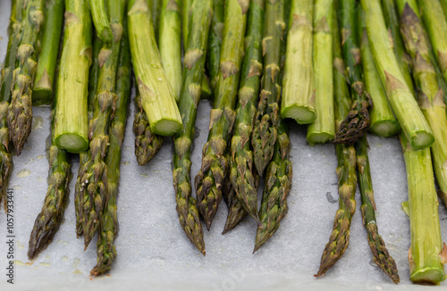 Nahaufnahme von dem im Ofen gebratenen Spargel mit Salz und Olivenöl auf dem Ofenblech mit Backpapier. Aufnahme von vorne.