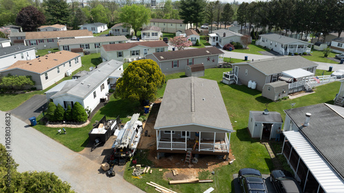 Fotografija Aerial view shows mobile, manufactured homes lined along a tranquil street, surrounded by well-maintained lawns and trees