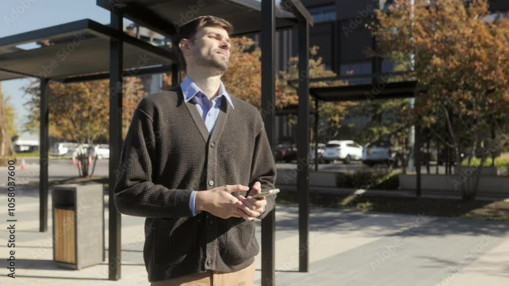 Thoughtful Man in Casual Attire Waits at City Station, Checking Time Thoughtful Man in Casual Attire Waits at City Station, Checking Time