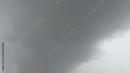 A cloudy sky with a mix of dark gray and lighter gray clouds. The clouds are thick and appear to be moving quickly. There is a distinct line separating the dark and light areas of the sky.