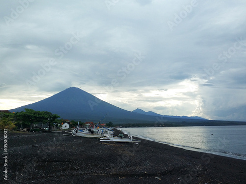 Calm ocean waves on a black beach with the majestic Agung volcano on the horizon on the tropical island of Bali. photo