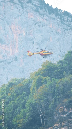 Securite Civile or a civil defense agency helicopter at work in the French Alps close to Grenoble. Vertical video photo