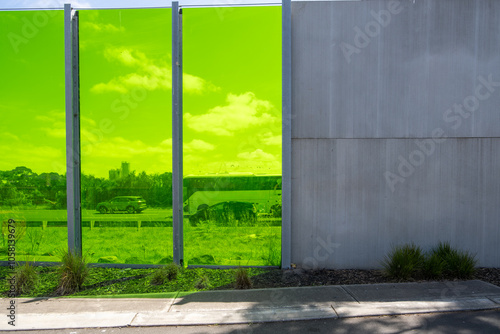 Wallpaper Mural Translucent green noise barrier panels line an urban roadway, providing both sound protection and an artistic element to the streetscape. Modern acoustic barriers and functional infrastructure. Torontodigital.ca