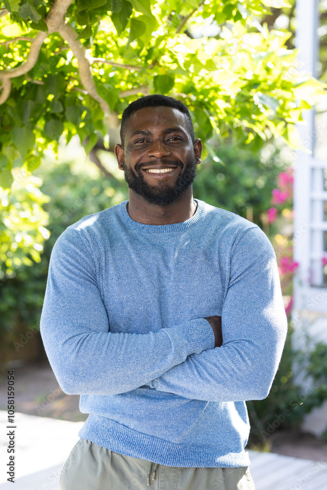 Smiling African american man in blue sweater standing outdoors, enjoying sunny day Smiling African american man in blue sweater standing outdoors, enjoying sunny day