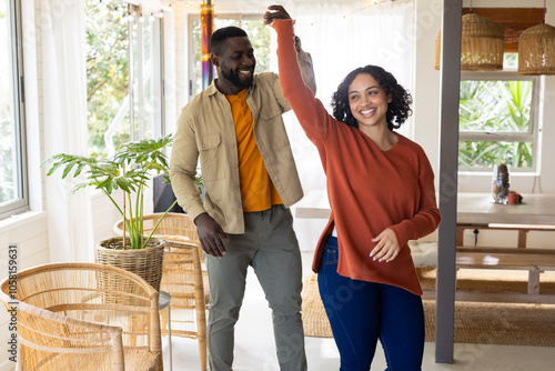 multiracial couple dancing joyfully at home, celebrating Thanksgiving together with happiness photo