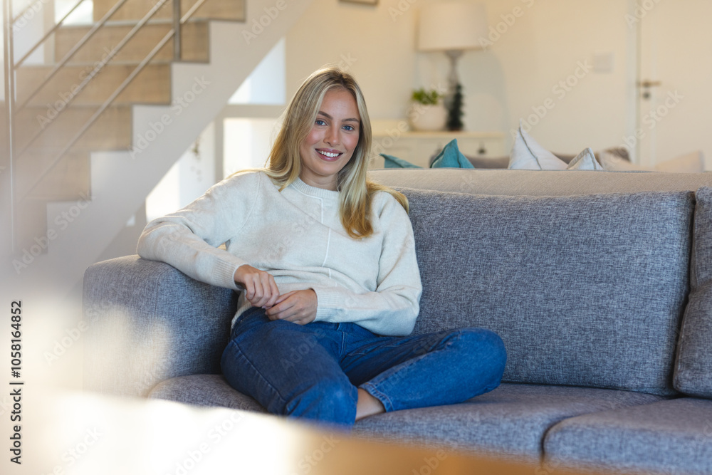 Smiling woman relaxing on cozy sofa at home, enjoying peaceful afternoon Smiling woman relaxing on cozy sofa at home, enjoying peaceful afternoon
