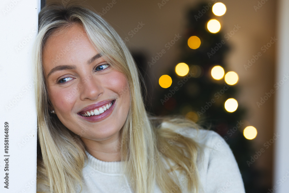Smiling woman enjoying festive holiday season with Christmas tree in background Smiling woman enjoying festive holiday season with Christmas tree in background