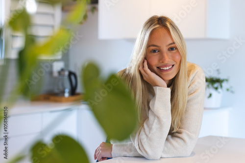 Smiling woman in cozy sweater leaning on kitchen counter at home photo