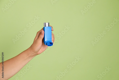 Woman holding asthma inhaler on olive background, closeup. Space for text photo