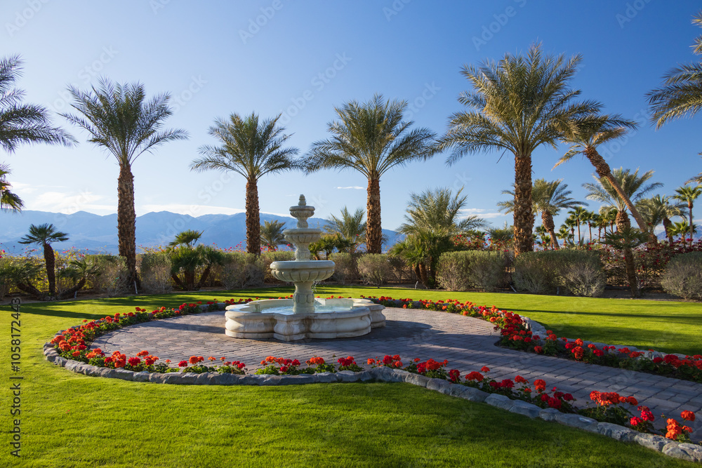 Obraz premium Tiered fountain with palm trees and red flowers