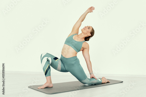Fitness Trainer Demonstrating Deep Side Stretch on Mat.