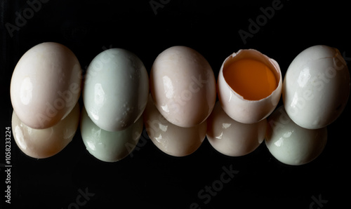 Obraz na płótnie Five raw duck eggs are sitting in a row with an egg broken in half showing the yolk and white egg with reflection on dark background. use it as your Wallpaper, Poster and Space for text, Selective foc w salonie