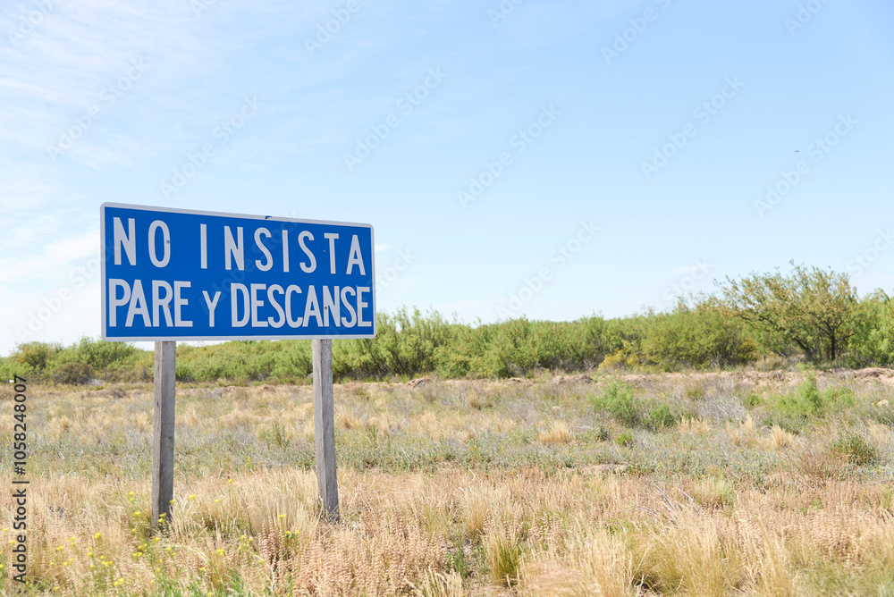 Warning sign for drivers on a monotonous, straight road with high risk of falling asleep. Text: Do not insist, stop and rest. Warning sign for drivers on a monotonous, straight road with high risk of falling asleep. Text: Do not insist, stop and rest.