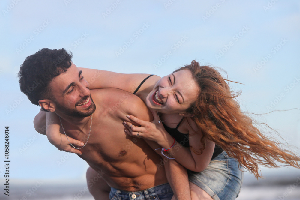 young playful couple having fun on the beach by the ocean on summer day young playful couple having fun on the beach by the ocean on summer day