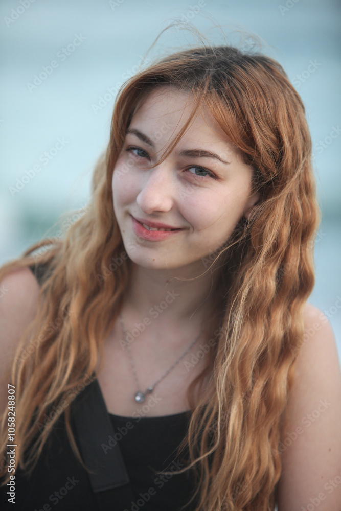 portrait of cheerful teenage girl outdoors at dusk with ocean and sky in background portrait of cheerful teenage girl outdoors at dusk with ocean and sky in background