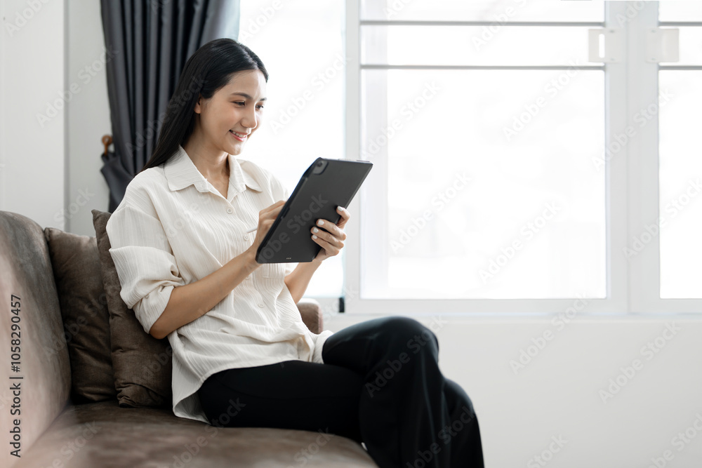 Young caucasian woman sitting alone on cozy sofa working on tablet. Freelancer in calm and cozy living room coding. Remote working in comfortable environment. Business concept Young caucasian woman sitting alone on cozy sofa working on tablet. Freelancer in calm and cozy living room coding. Remote working in comfortable environment. Business concept