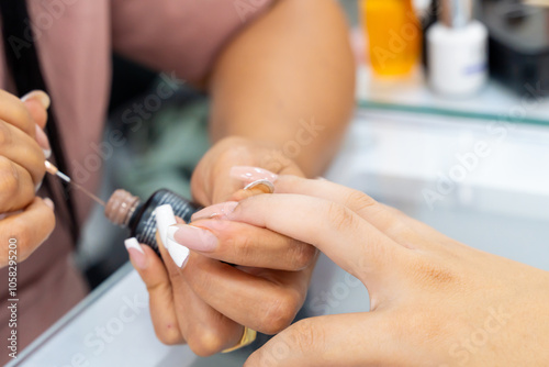 Colombian latina woman in nail spa. Manicurist doing nail cleaning and decoration. Beauty and fashion.