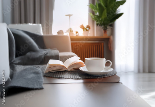 A cozy living room with a cup of coffee, an open book, and a warm blanket on a couch.