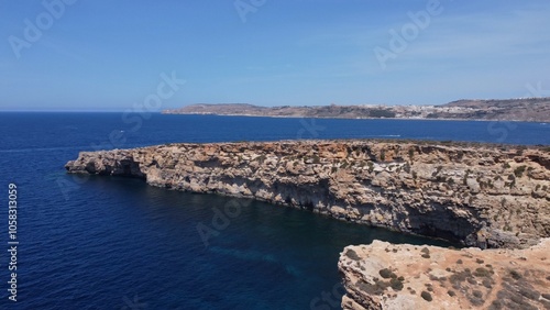 Aerial view of the sea caves of Cominotto uninhabited island near Comino, Maltese islands. Seagull flying in the frame. High quality photo