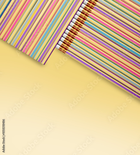 Colorful pencils arranged in diagonal composition on pastel yellow background.