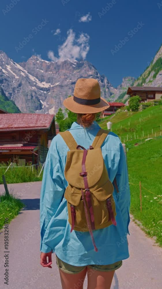 An attractive girl in a blue shirt and a fashionable hat spends her holidays alone, traveling through the Alpine meadows. Tourist with a backpack travels through Switzerland with incredible views An attractive girl in a blue shirt and a fashionable hat spends her holidays alone, traveling through the Alpine meadows. Tourist with a backpack travels through Switzerland with incredible views