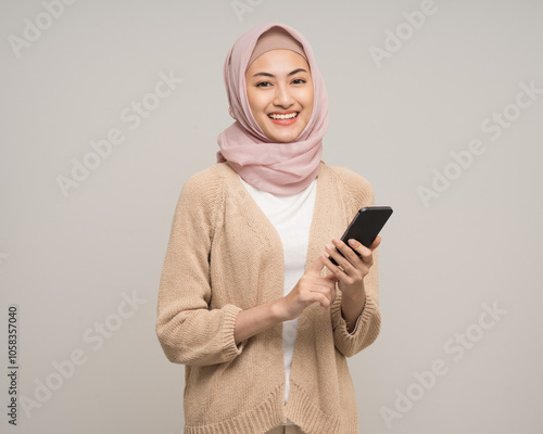 Photography Portrait happy young asian muslim woman holding smartphone standing on isolated white background