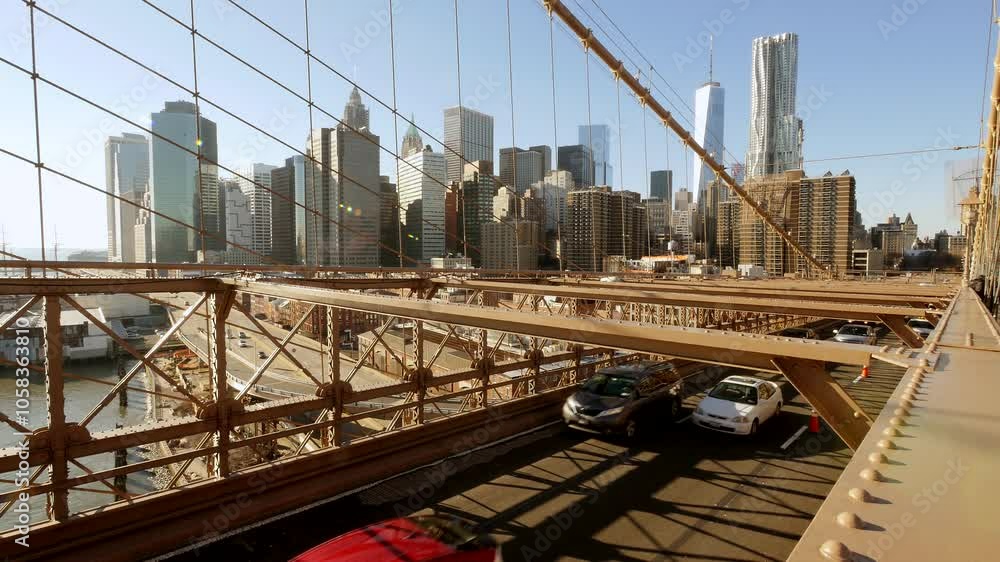 Sunny day view of NYC skyline from Brooklyn Bridge with iconic buildings and steel cables Sunny day view of NYC skyline from Brooklyn Bridge with iconic buildings and steel cables