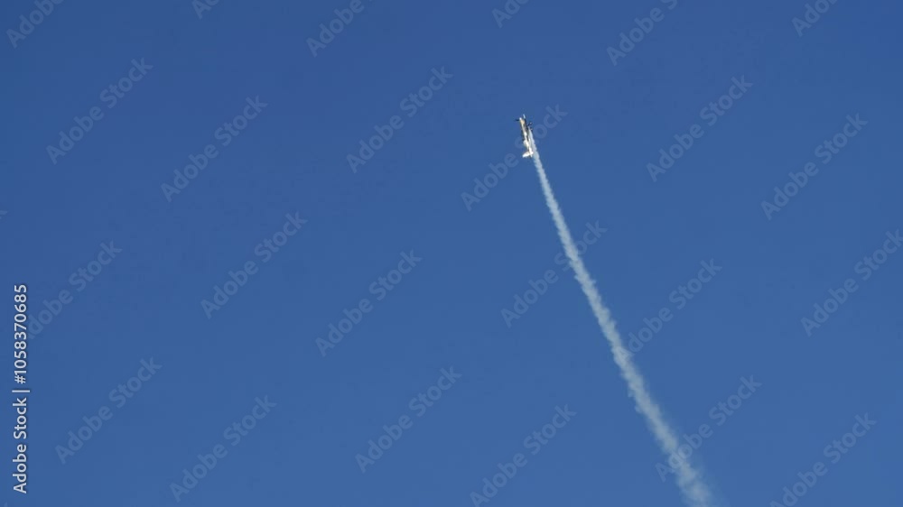Airplane executes steep spinning climb in slow motion at Oeiras airshow, highlighting intense aerial maneuvers against open blue sky, smoke trailing behind Airplane executes steep spinning climb in slow motion at Oeiras airshow, highlighting intense aerial maneuvers against open blue sky, smoke trailing behind