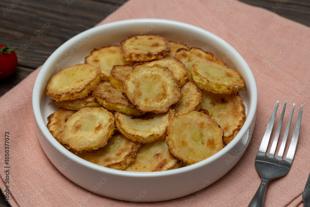 Slices of fried crookneck in oil with garlic on a wooden background Slices of fried crookneck in oil with garlic on a wooden background