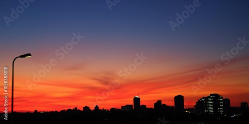 A street lamp glowing against a colorful sunset sky, casting a warm light, street lamp, glowing photo