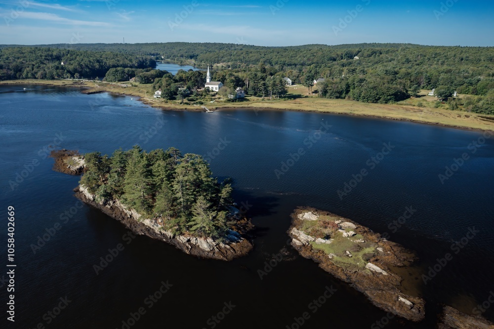 Fototapeta premium Island with trees and chursh in the distance on the Kennybec River, Phippsburg, Maine, United States.