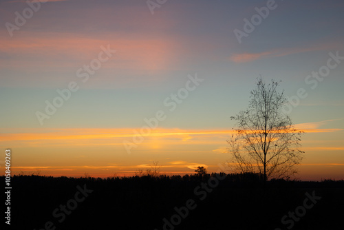 Beautiful colorful autumn sunrise skies over the rural landscape of Latvia. Seasonal scenery of Northern Europe.