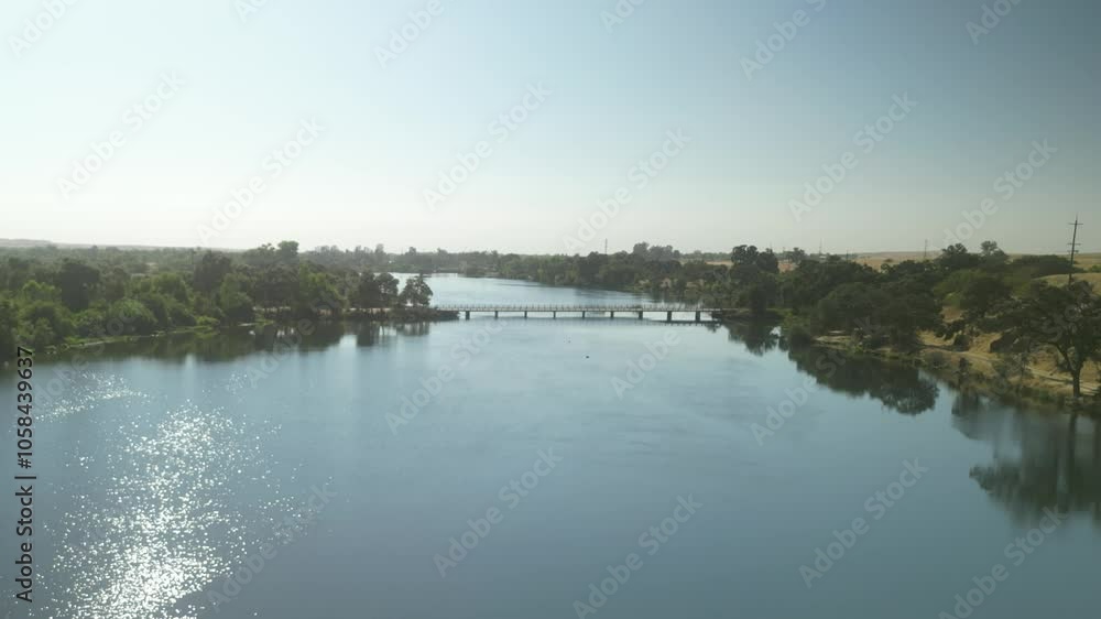 Aerial pullback and pan across calm Merced River with Merced Bridge and natural scenery in California, wide perspective Aerial pullback and pan across calm Merced River with Merced Bridge and natural scenery in California, wide perspective
