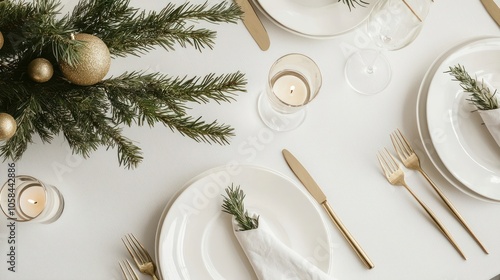 A minimalist Christmas table with white porcelain plates, a single green branch as a centerpiece, and gold accents like napkin rings and candleholders photo