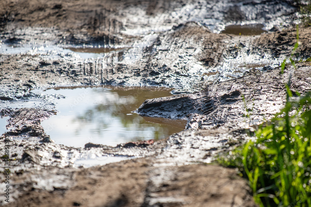 A muddy field with a puddle of water in the middle A muddy field with a puddle of water in the middle