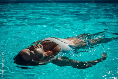 Woman relaxing swimming pool. Happy woman in a blue swimsuit floating in the pool, look form above