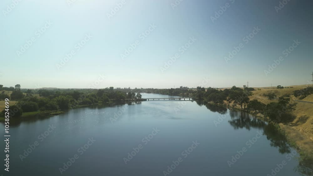 Merced Bridge over calm river water reflecting sky with serene dry desert California landscape, wide aerial view Merced Bridge over calm river water reflecting sky with serene dry desert California landscape, wide aerial view