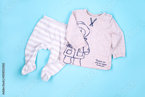 Set of warm baby clothes with bodysuits for boy on blue background. Collection of cute  baby clothes. Gift for the birth of a boy, help for those in need, second hand photo