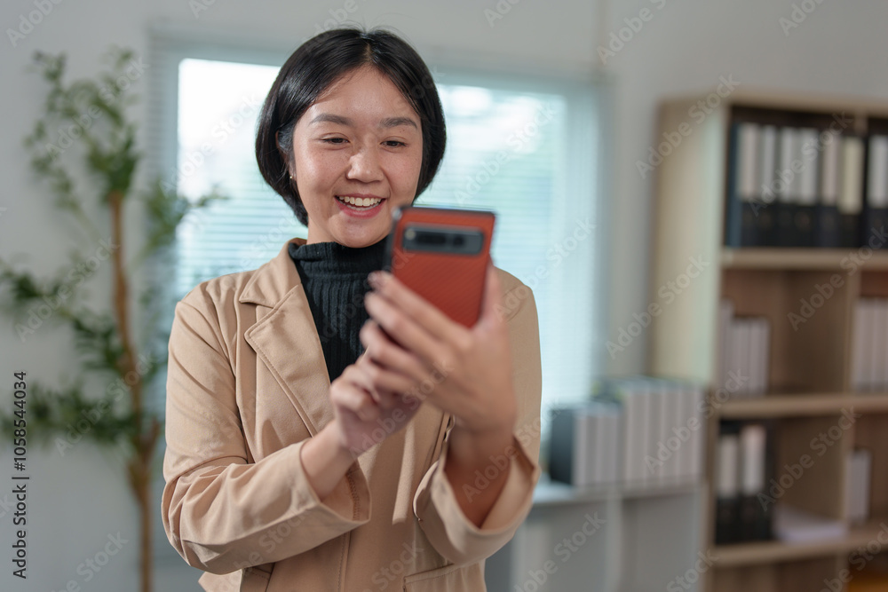 Attractive Asian businesswoman standing on the phone talking about real estate projects and chatting with happy smiles at the office. Attractive Asian businesswoman standing on the phone talking about real estate projects and chatting with happy smiles at the office.